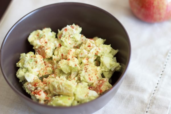 brown bowl with avocado egg salad topped with paprika