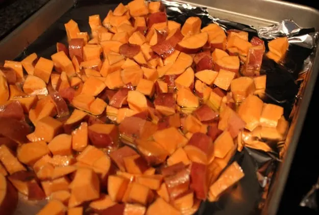 chopped sweet potatoes on aluminum foil lined baking sweet drizzled in olive oil