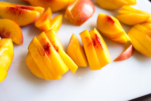 cut up peaches on white cutting board