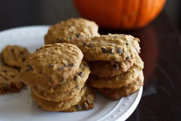 Pumpkin oatmeal chocolate chip cookies stacked on a white plate