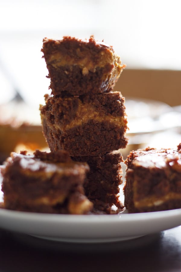 Pumpkin cheesecake brownies stacked on white plate