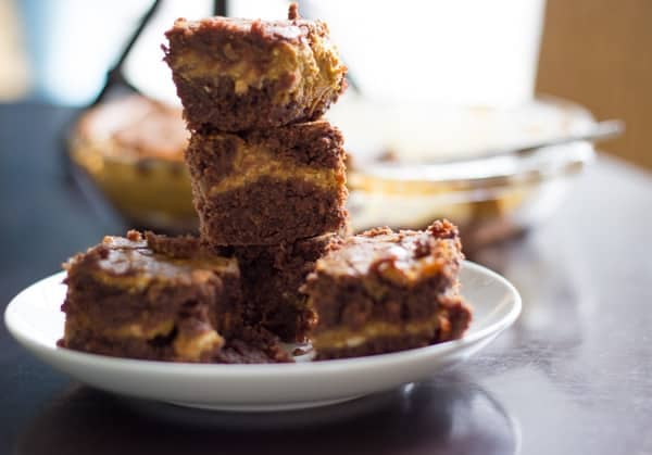 pumpkin cheesecake brownies stacked on a white plate