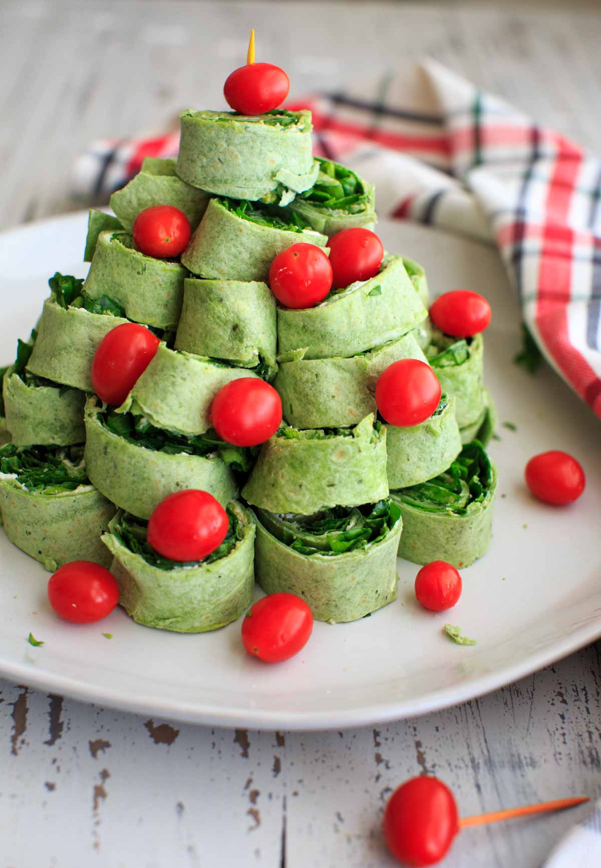 red and green Christmas tree pita pinwheel appetizer on white plate with holiday napkin