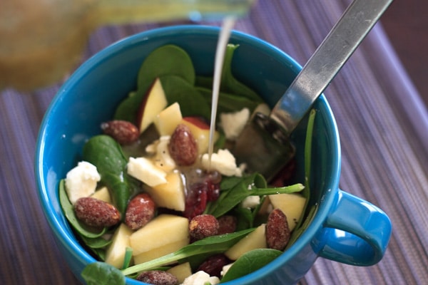 Spinach salad with apple in a blue mug bowl with fork