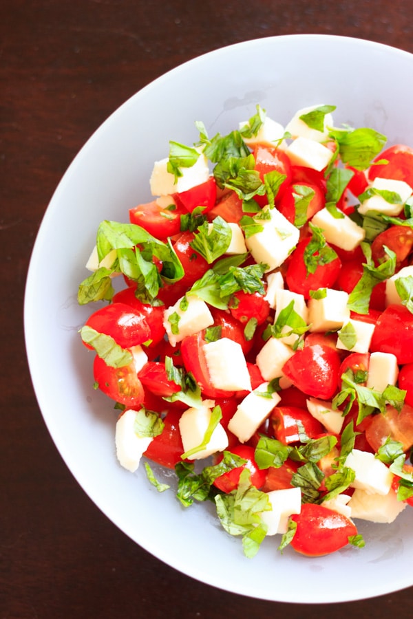 half shot of caprese salad in clear bowl before adding olive oil