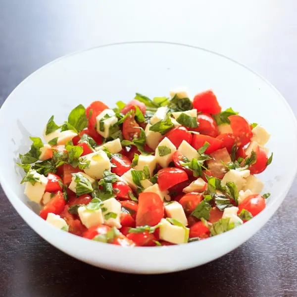 chopped caprese salad in clear bowl before adding balsamic