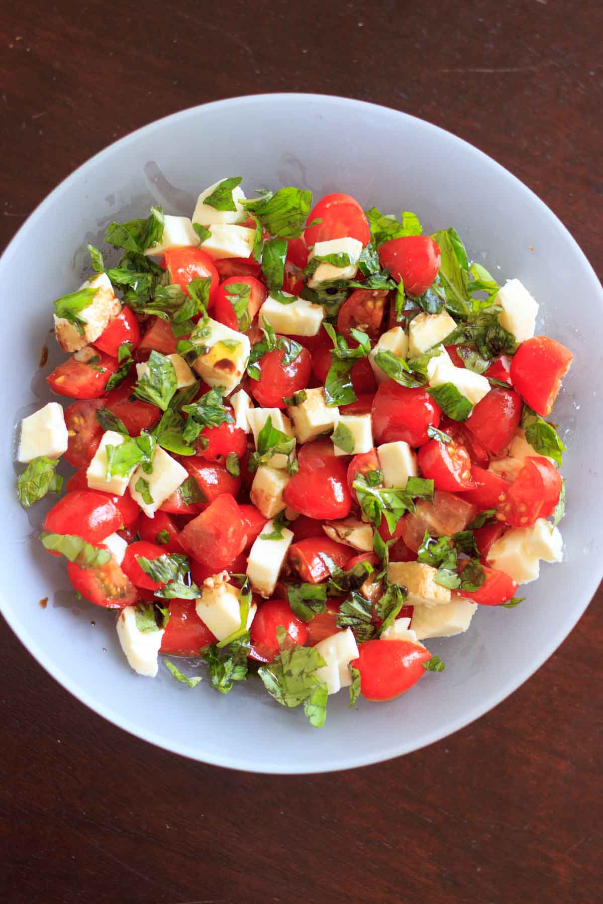 A delicious recipe for chopped Caprese salad! Only 5 ingredients for his crowd-pleasing vegetarian appetizer dish that is so easy to toss together for any occasion. Summer cookouts, potluck dinners, family apps, or a lunch for one. Easy to make in a big batch for many people or a small amount for a few side dishes. Gluten-free and low carb with fresh basil, mozzarella, chopped tomato, and balsamic vinegar or glaze!