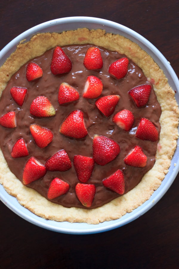 Nutella pudding in a homemade tart crust with cut strawberries on top