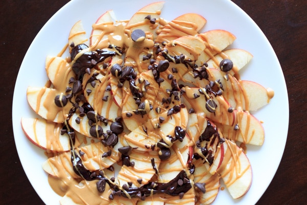apple nachos with peanut butter and chocolate drizzle on white plate