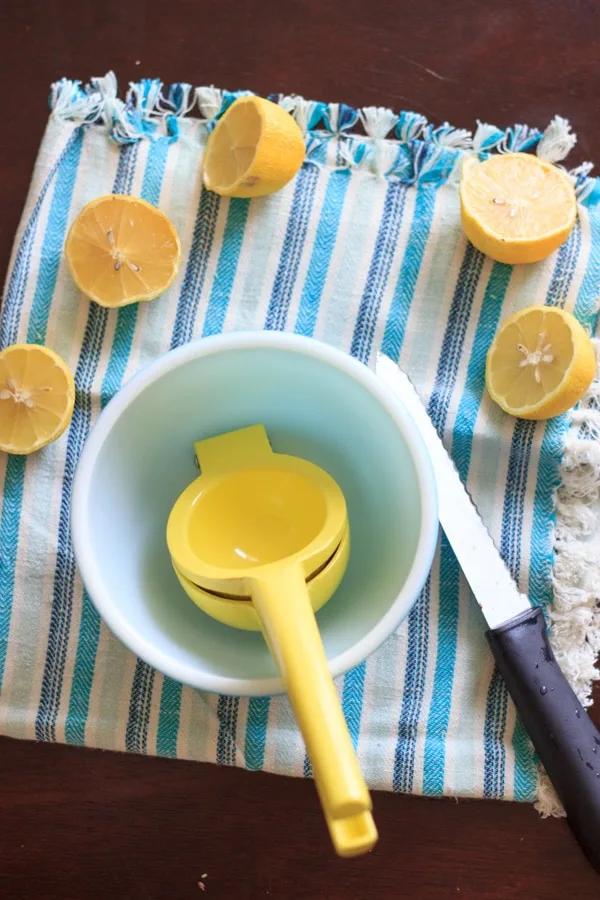squeezing lemon juice in a bowl for blueberry mint lemonade