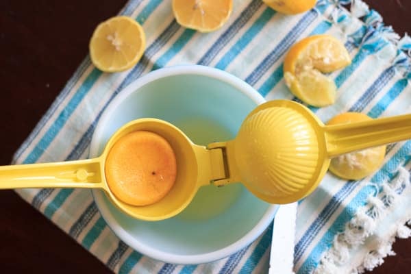 squeezing lemon juice in a bowl for blueberry mint lemonade