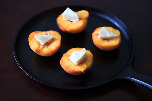 4 pieces of halved peaches with brie uncooked on skillet