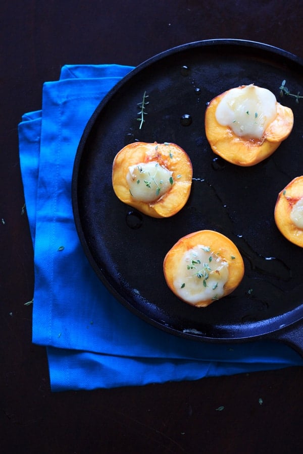 halved peaches with brie and thyme on skillet with blue napkin underneath