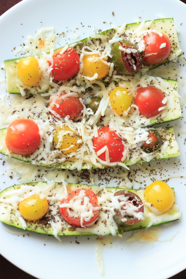 4 Quick and easy zucchini boats with tomato and shredded cheese with herbs