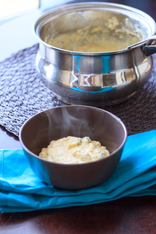 summer grits in brown bowl in front of serving pot