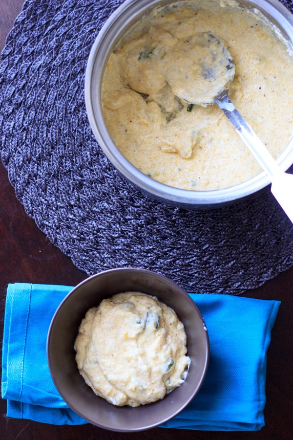 overlook view of cooked grits dish in serving pot and single bowl on blue napkin