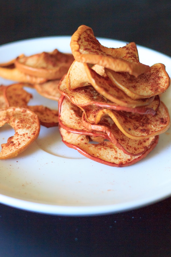 baked cinnamon apple chips stacked on white plate