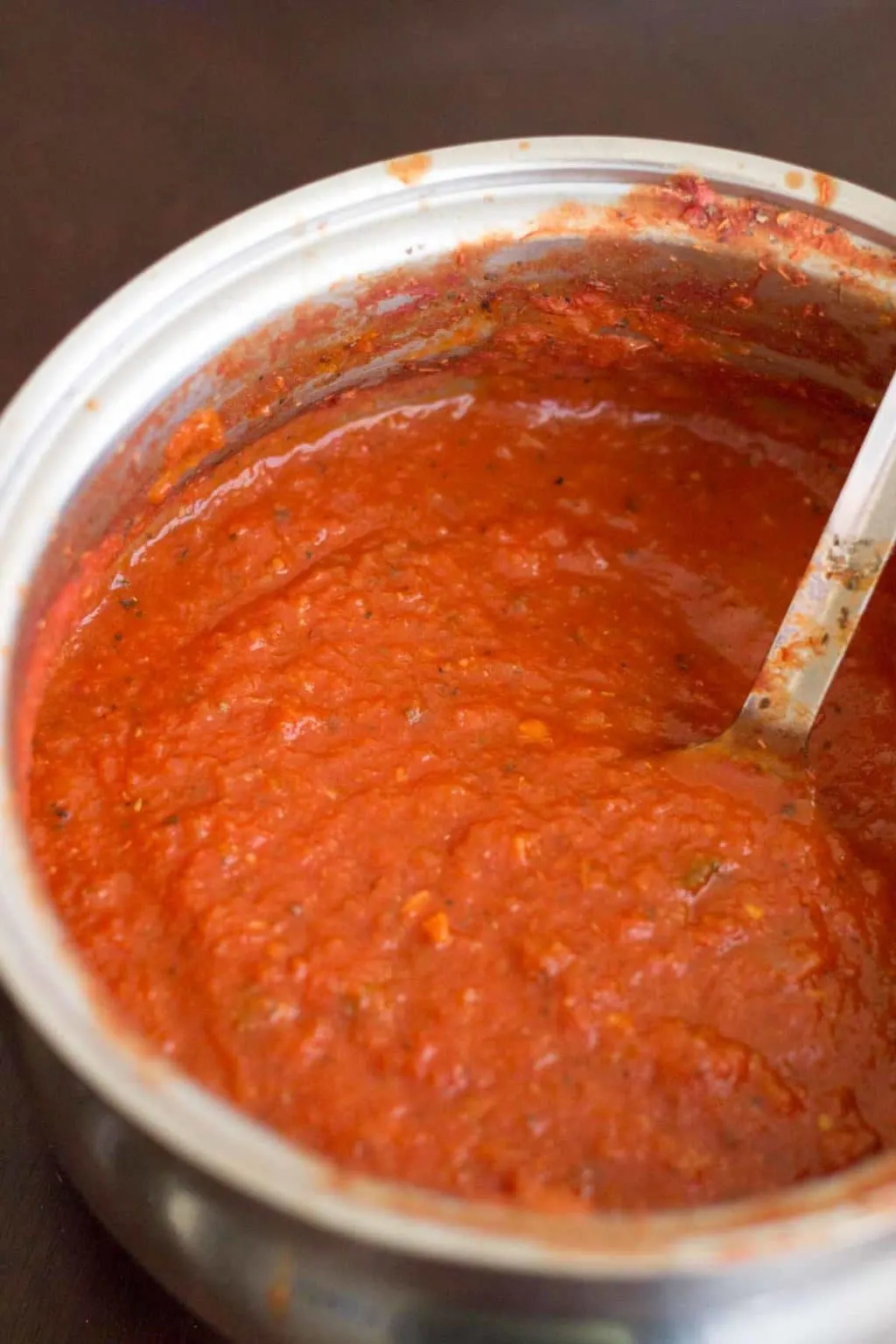 Homemade marinara sauce in a stock pot with large spoon
