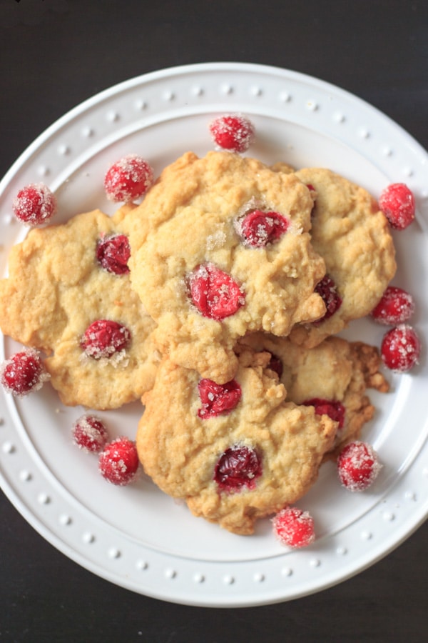 sugared cranberry cookies on white plate with extra cranberries