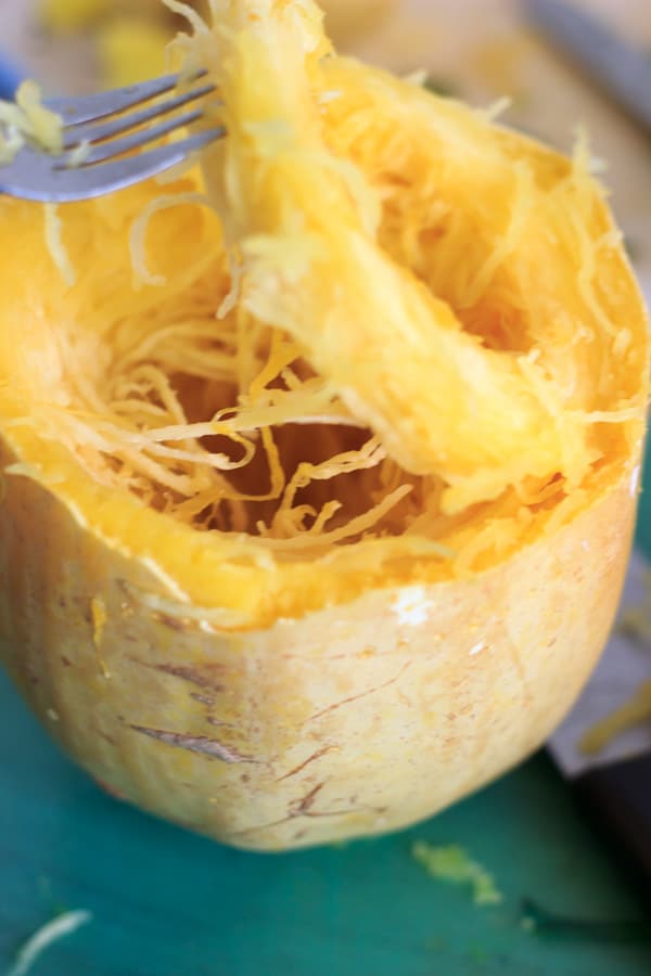 fork lifting ring of cooked spaghetti squash out of rind