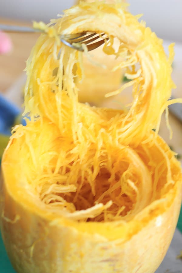 fork lifting ring of cooked spaghetti squash out of rind