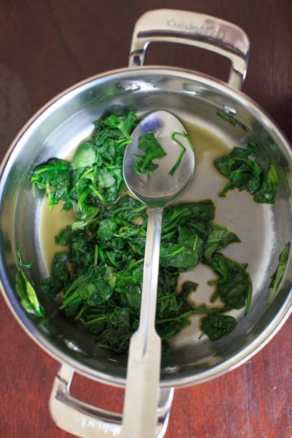 sauteed spinach in pot with spoon.