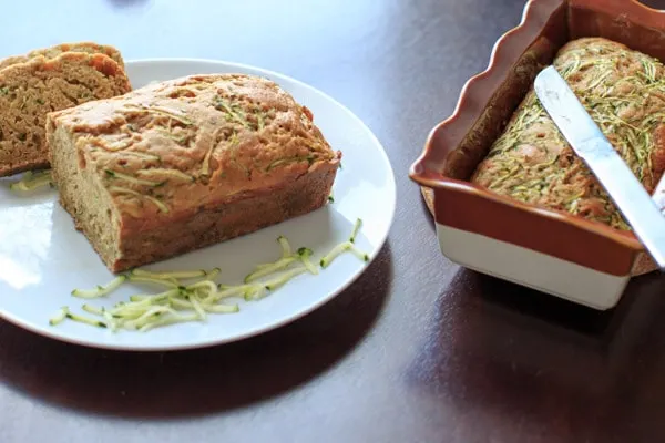 Skinnier Zucchini Bread on white plate next to second loaf in bread pan