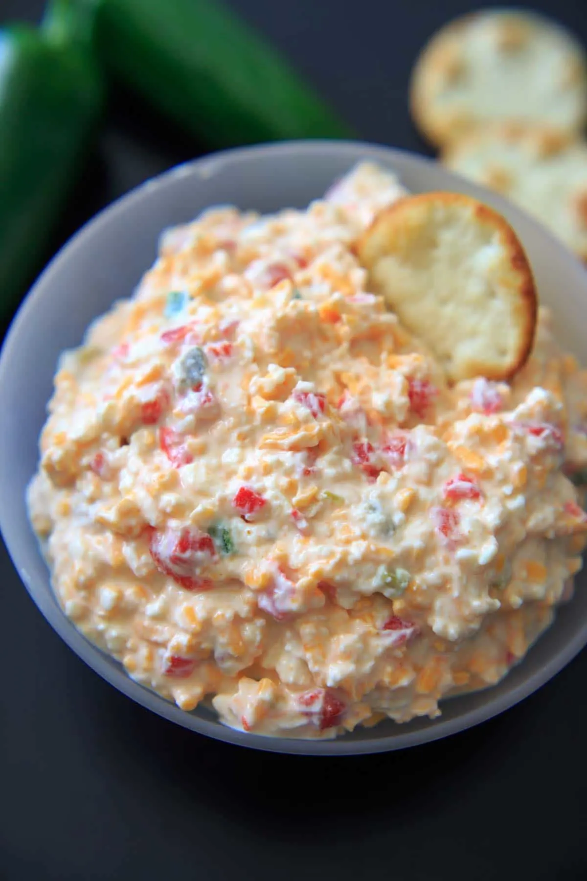 a cracker dipped into a bowl of jalapeno pimento cheese