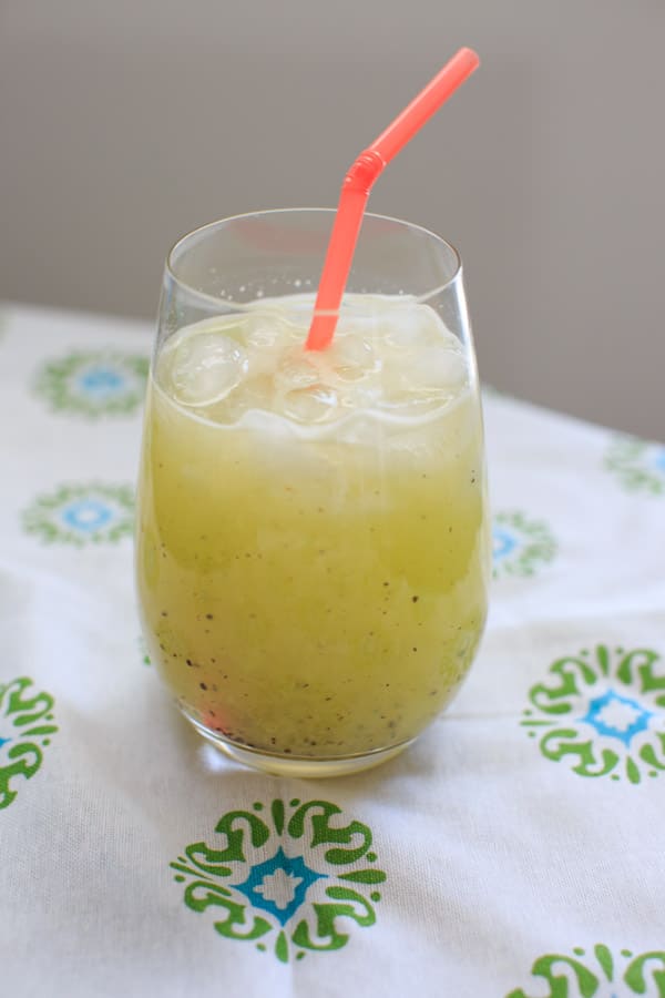 Homemade Kiwi Lemonade in clear glass with pink straw