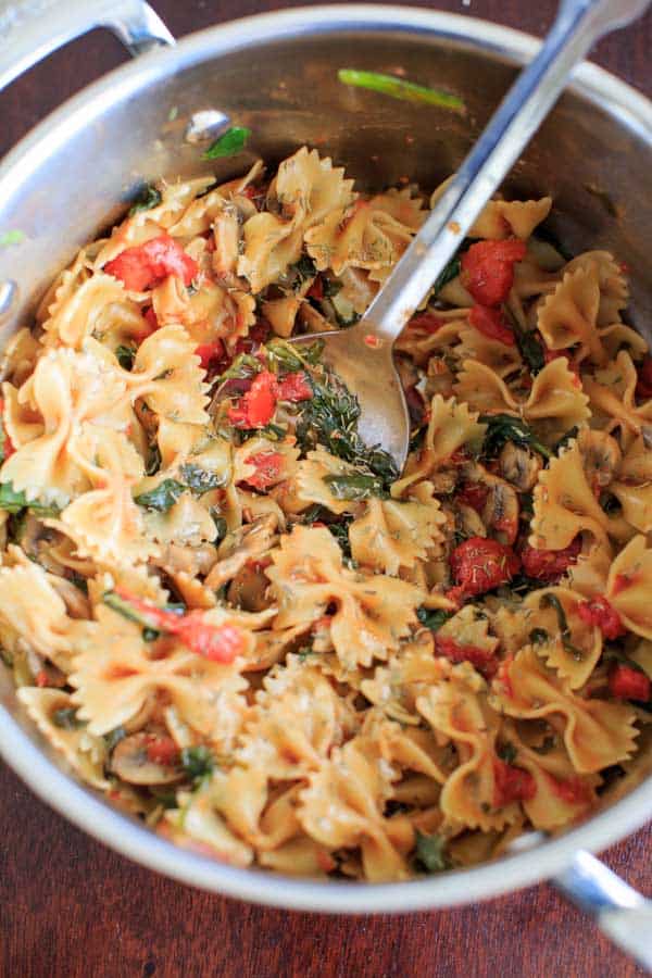 spinach and mushroom pasta in pot with serving spoon