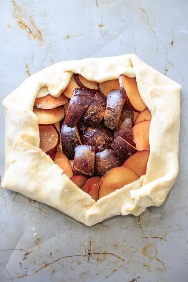 cut up plums wrapped in puff pastry before baking galette