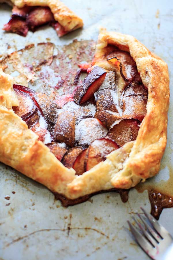 Puff Pastry Plum Galette on baking sheet with a serving sliced out