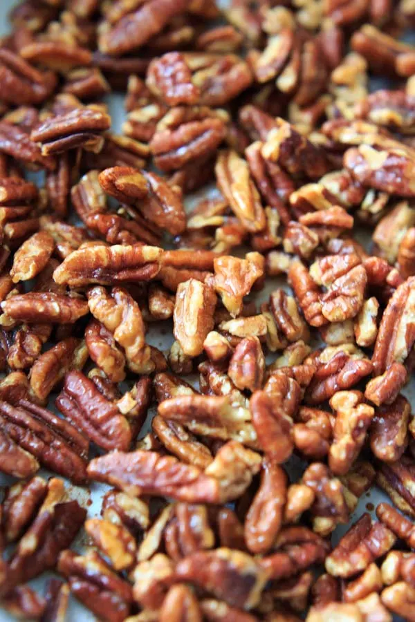 close up of honey roasted pecans on baking sheet