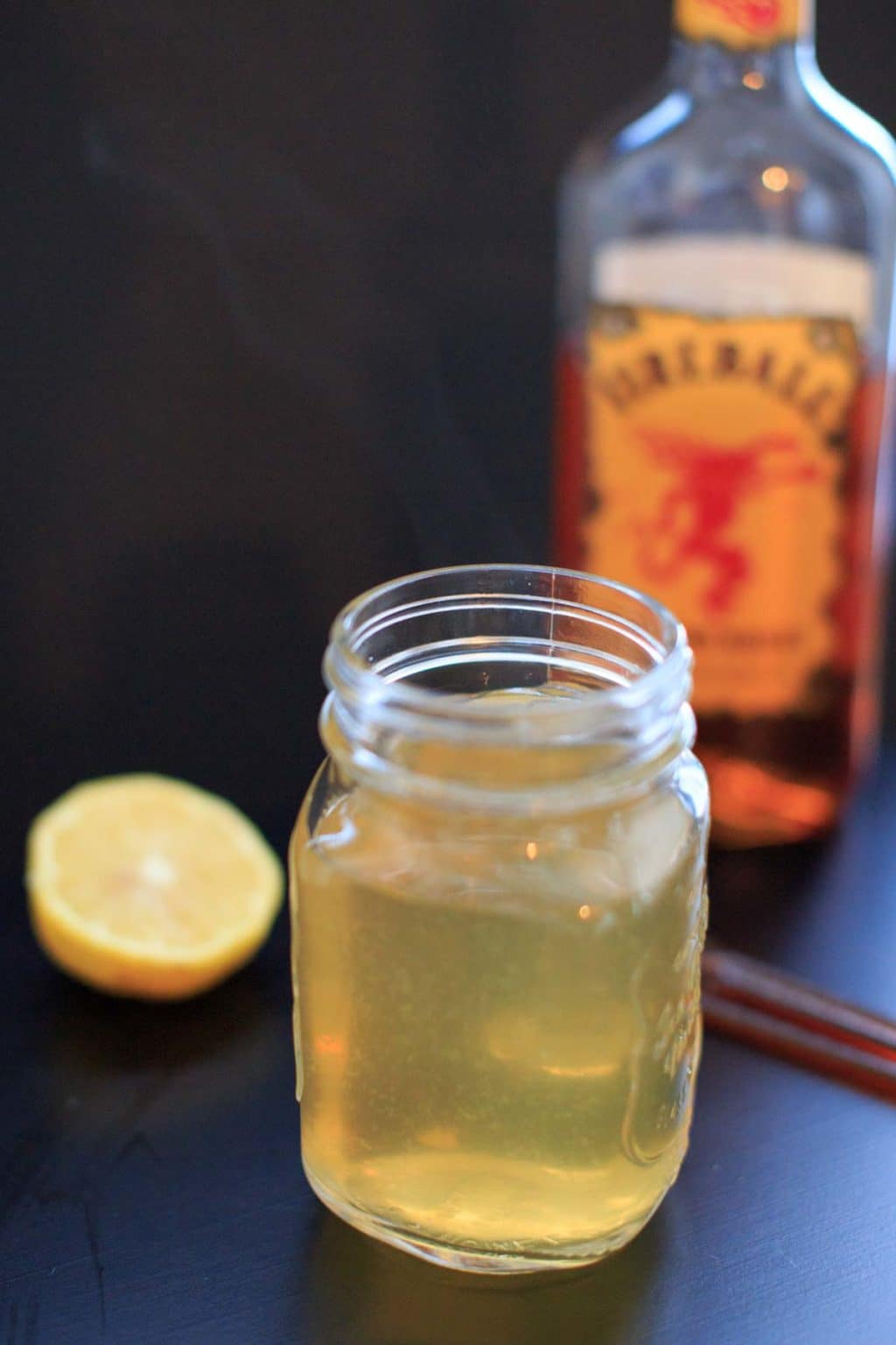 Fireball Hot Toddy  in a clear mason jar with fireball in background