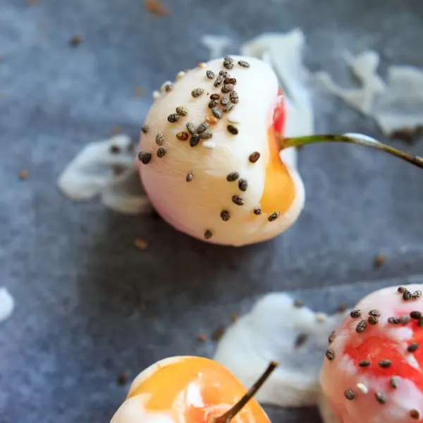 close up of cherry dipped on greek. yogurt and topped with chia seeds