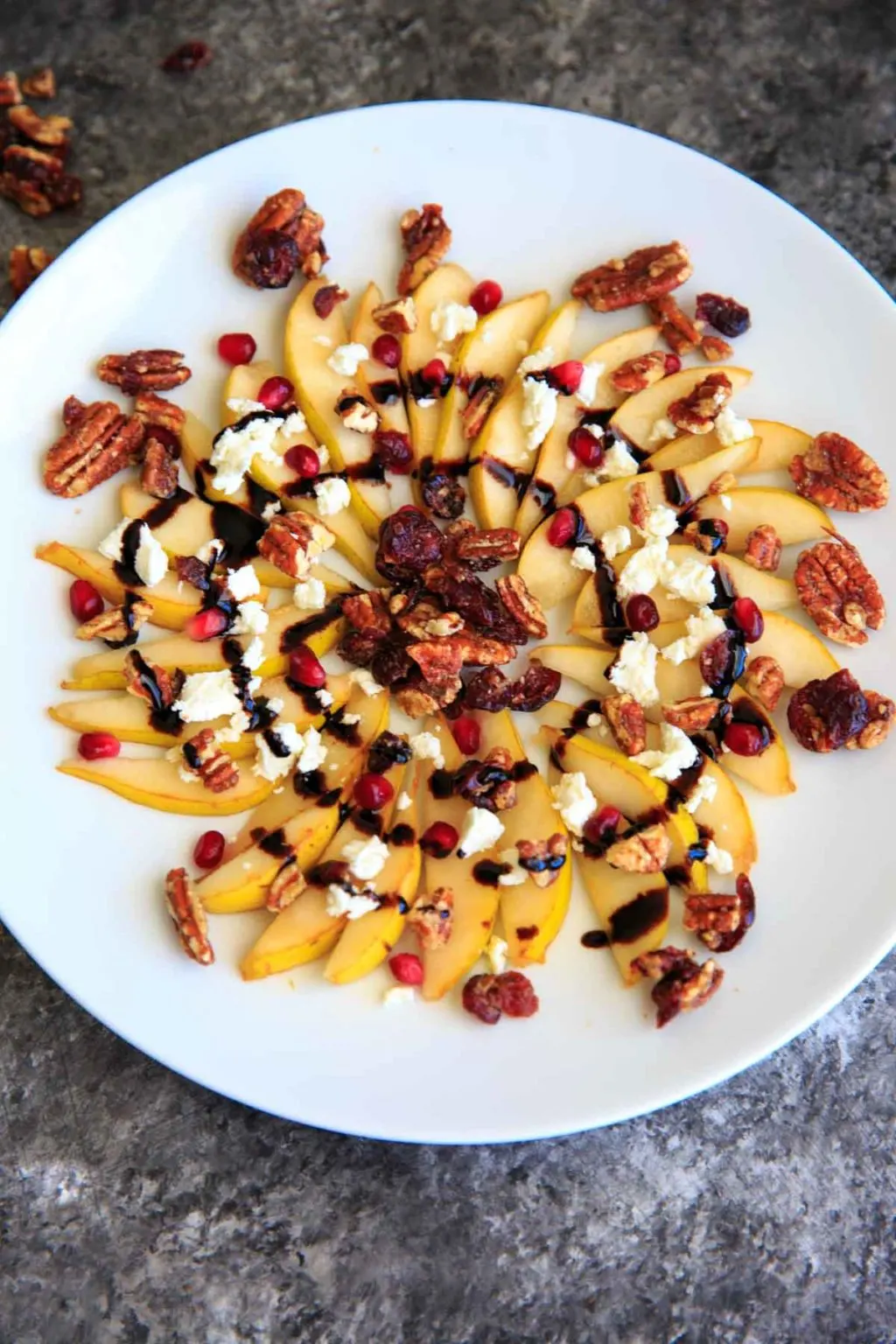 Sweet and savory pear nachos with glazes pecans, chevre cheese, pomegranate seeds and balsamic. A unique snack or dessert!