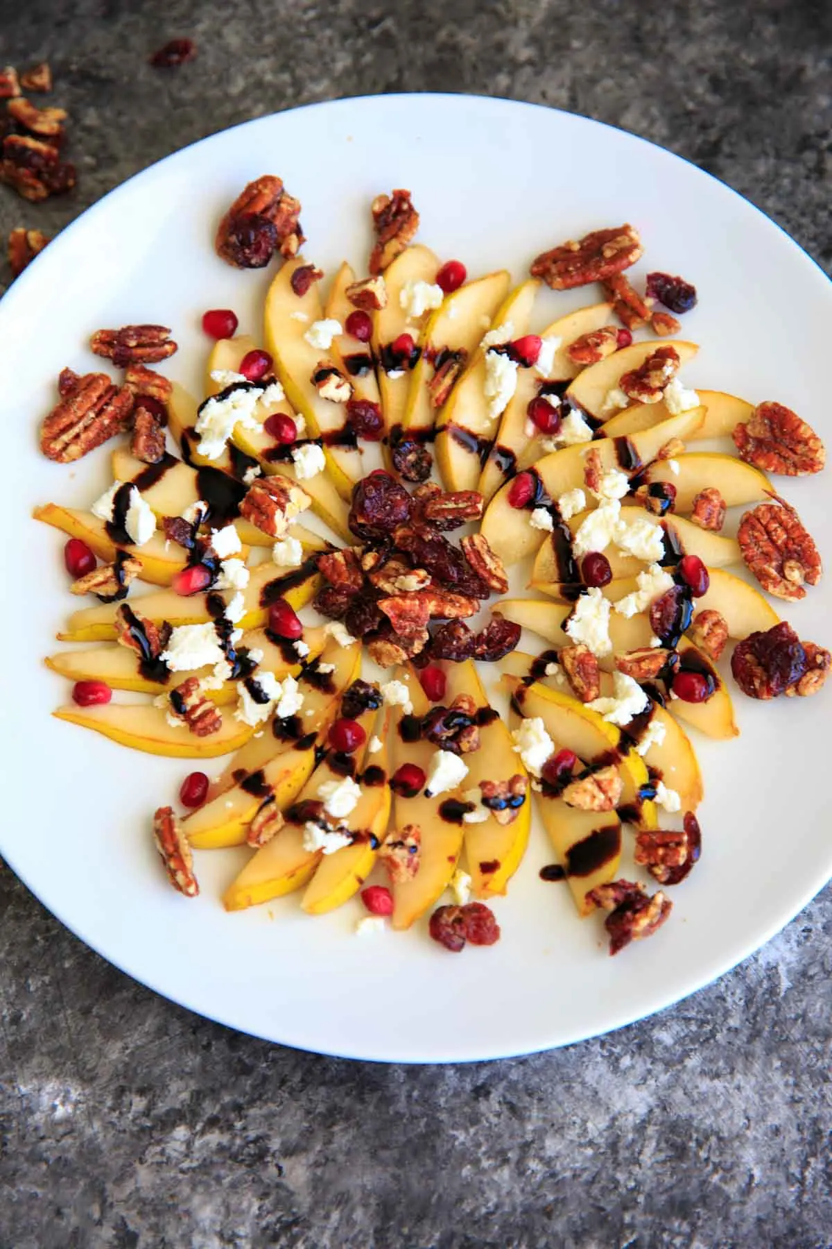 Sweet and savory pear nachos with glazes pecans, chevre cheese, pomegranate seeds and balsamic. A unique snack or dessert!