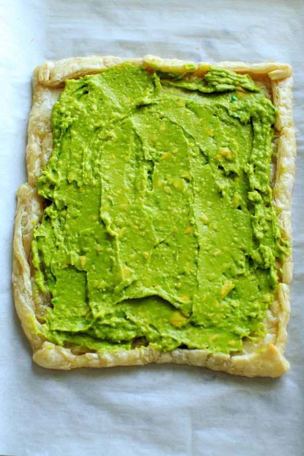 baked puff pastry with mashed avocado spread out on top