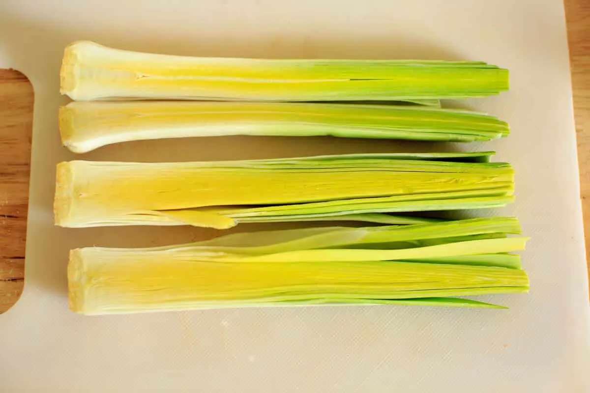 3 leeks cut in half on cutting board