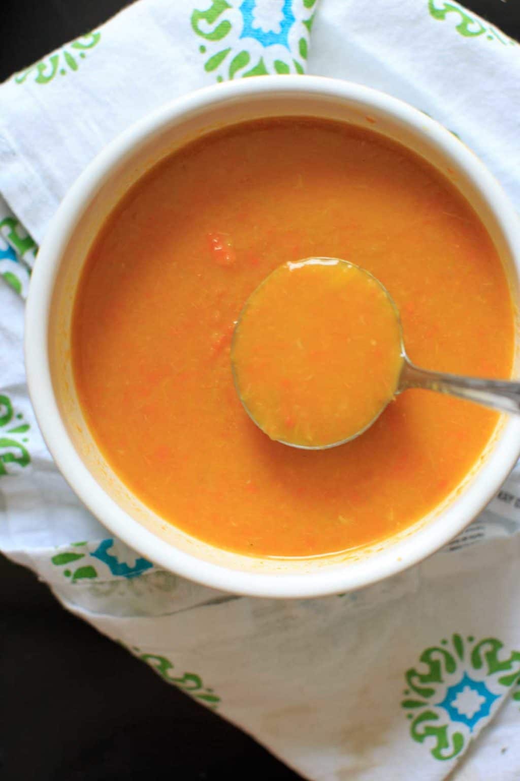Carrot and Leek Soup in white bowl with spoonful raised