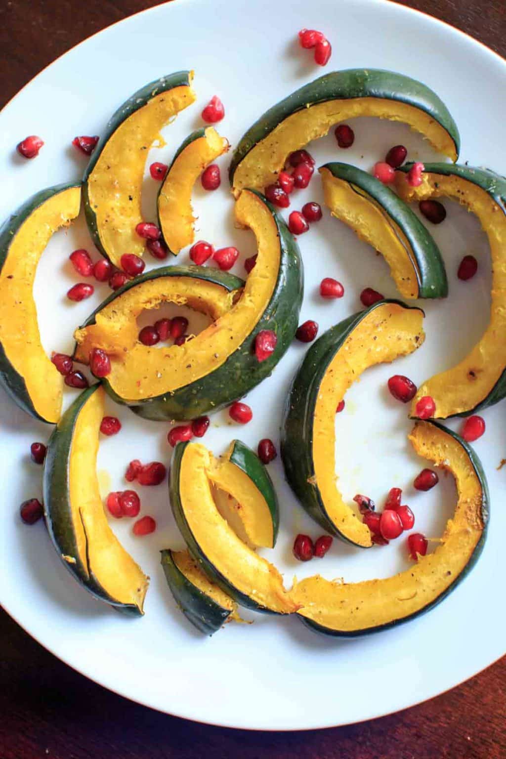 Roasted Acorn Squash with pomegranate seeds on white plate