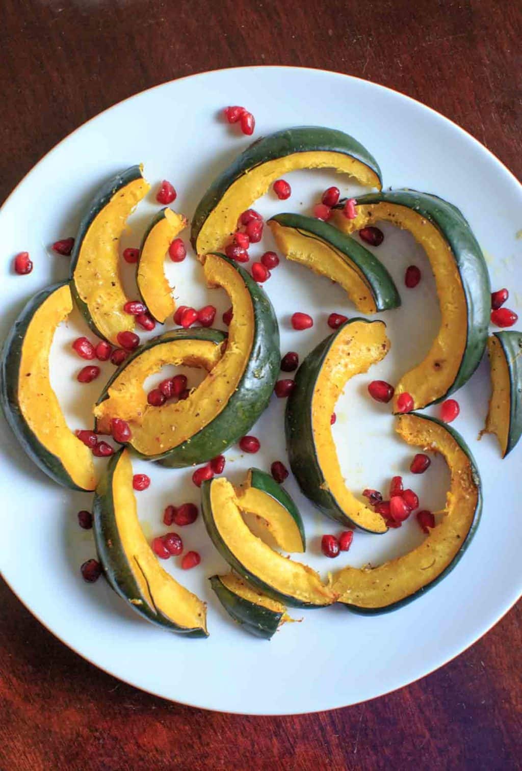 Roasted Acorn Squash with pomegranate seeds on white plate