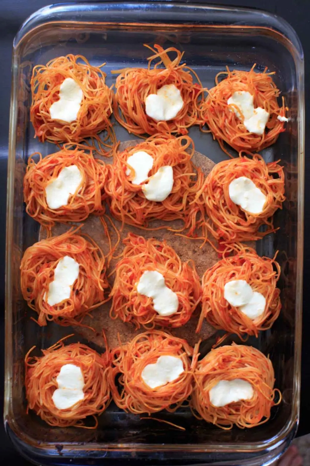angel hair nests in clear casserole dish after baking with cheese on top
