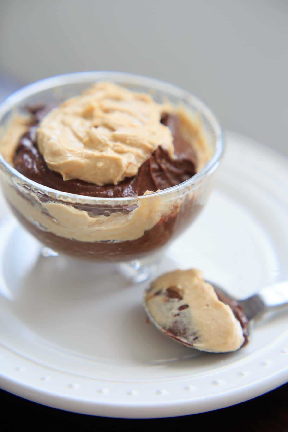 Vegan Chocolate Peanut Butter Mousse in dessert bowl, with spoonful resting next to it on white plate