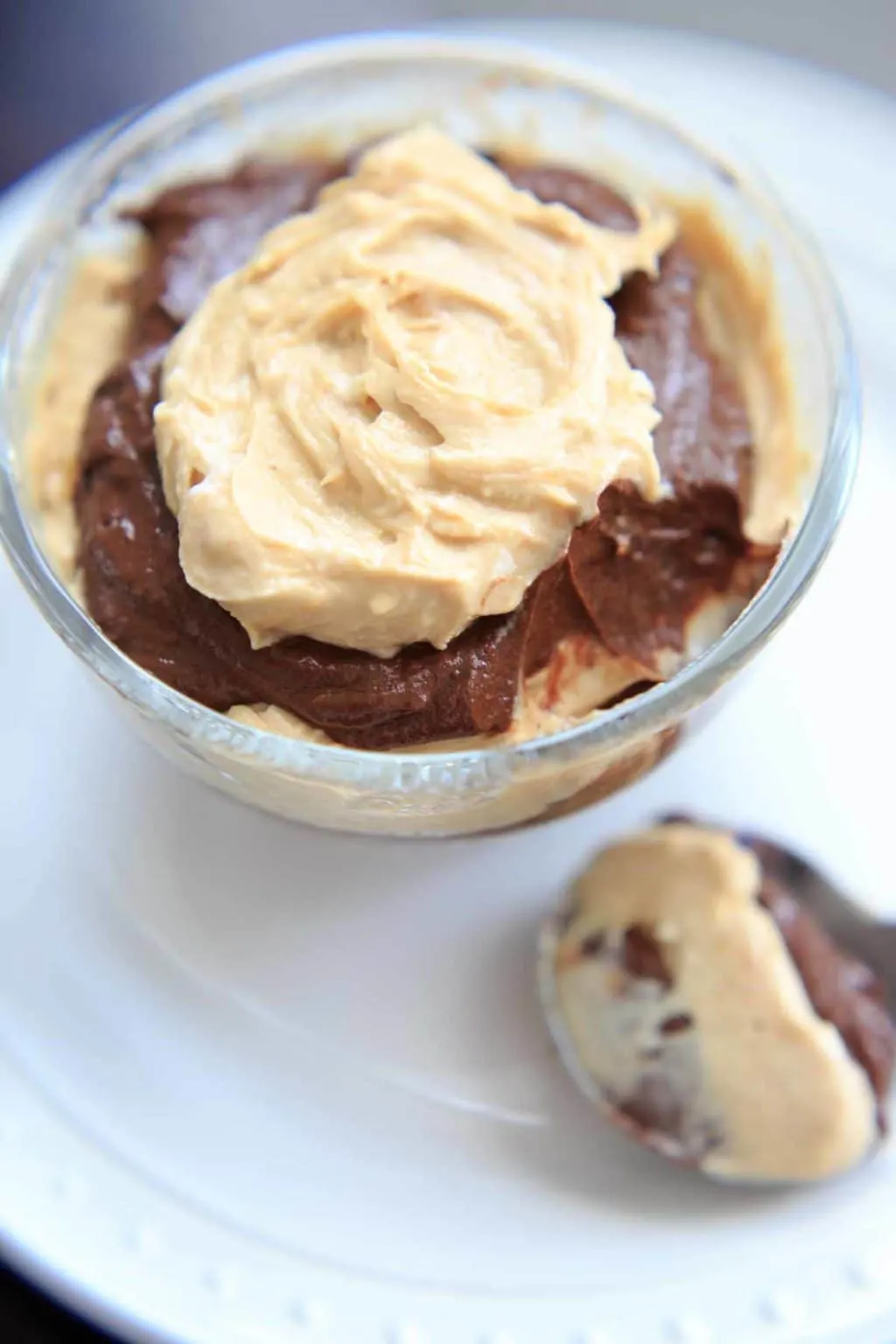 Vegan Chocolate Peanut Butter Mousse in dessert bowl, with spoonful resting next to it on white plate