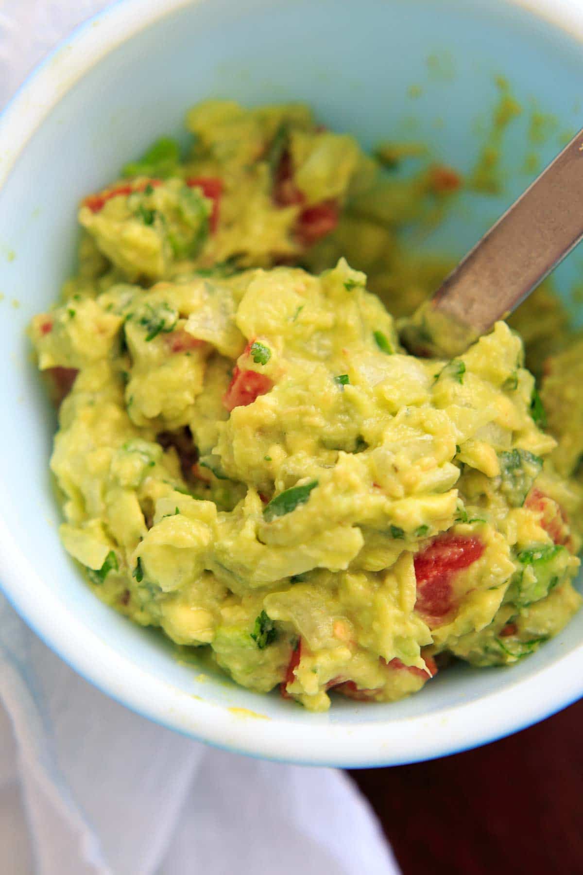 mashing up the best ever guacamole with a spoon in bowl
