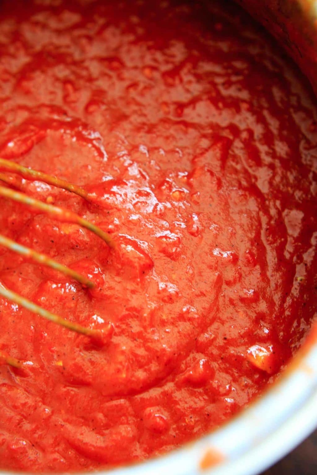 stirring homemade enchilada sauce with whisk