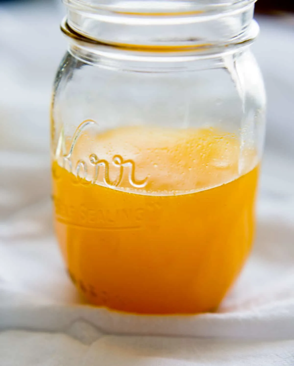 turmeric detox drink in clear mason jar on white cloth
