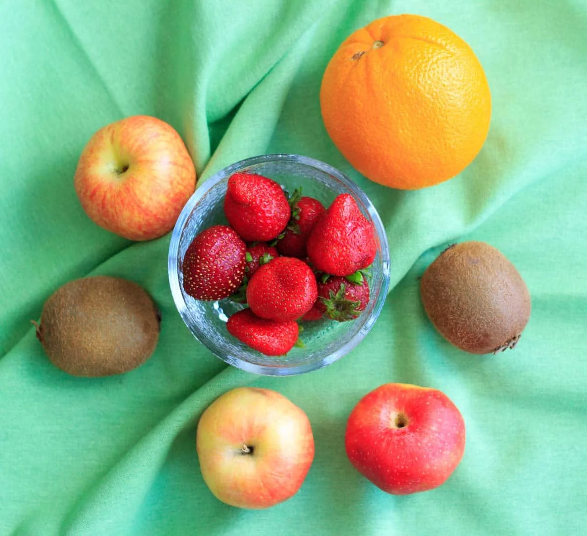 whole fruit before cutting for salsa recipe - bowl of strawberries in middle, surrounded by orange, apples and kiwis