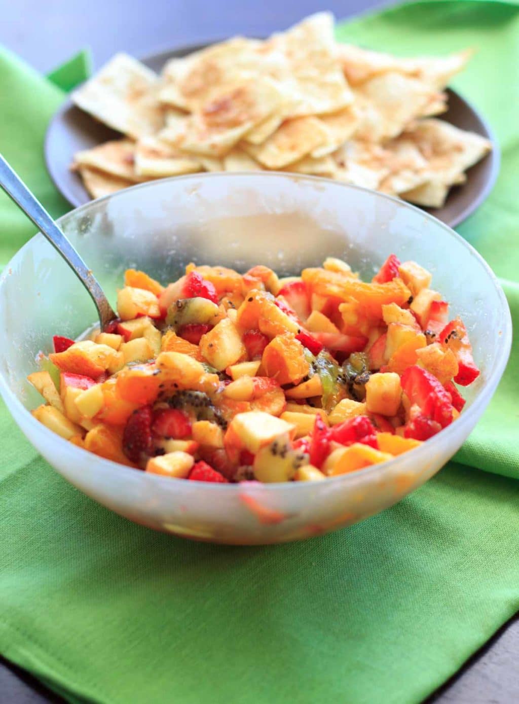 fruit salsa in clear bowl with cinnamon tortilla chips in background